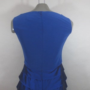 K&ouml;nnte beinhalten: Ein &auml;rmelloses, k&ouml;nigsblaues Kleid mit einem R&uuml;schenrock. Das Kleid hat ein schlichtes, elegantes Design und ist perfekt f&uuml;r einen besonderen Anlass.