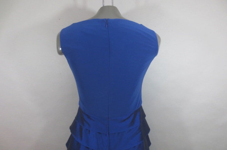 K&ouml;nnte beinhalten: Ein &auml;rmelloses, k&ouml;nigsblaues Kleid mit einem R&uuml;schenrock. Das Kleid hat ein schlichtes, elegantes Design und ist perfekt f&uuml;r einen besonderen Anlass.