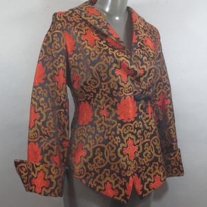 May include: A black, red, and gold brocade jacket with a mandarin collar and a tie closure. The jacket has a floral pattern.