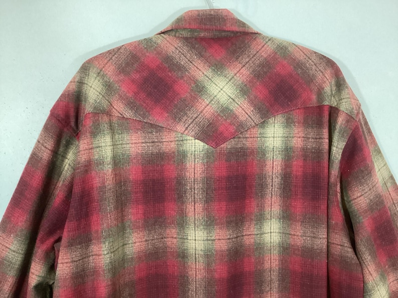 Puede incluir: Camisa a cuadros rojos, beige y marrones con un detalle de canes&uacute; puntiagudo en la espalda. La camisa tiene cuello abotonado y mangas largas. El estampado de cuadros es un dise&ntilde;o cl&aacute;sico.