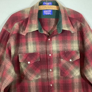 Puede incluir: Una camisa a cuadros roja, beige y verde con dos bolsillos delanteros y cierres de botones a presi&oacute;n de perlas. La camisa tiene un cuello verde y una etiqueta Pendleton.