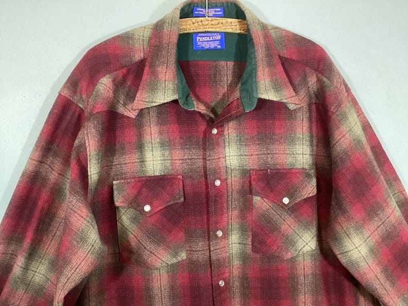 Puede incluir: Una camisa a cuadros roja, beige y verde con dos bolsillos delanteros y cierres de botones a presi&oacute;n de perlas. La camisa tiene un cuello verde y una etiqueta Pendleton.