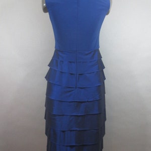 K&ouml;nnte beinhalten: Ein &auml;rmelloses Kleid in K&ouml;nigsblau mit einem Stufenrock. Das Kleid ist aus einem glatten, seidenartigen Stoff.