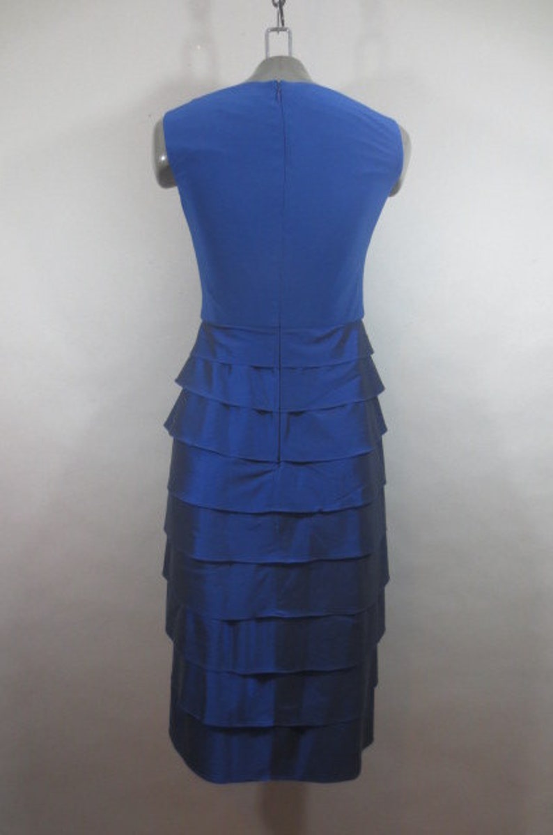 K&ouml;nnte beinhalten: Ein &auml;rmelloses Kleid in K&ouml;nigsblau mit einem Stufenrock. Das Kleid ist aus einem glatten, seidenartigen Stoff.