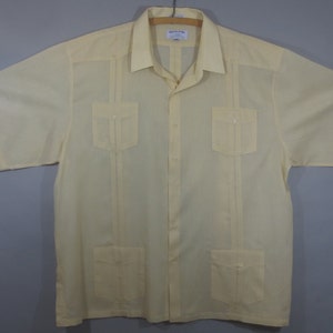 May include: A pale yellow short-sleeved button-down shirt with four pockets and a Cuban collar.