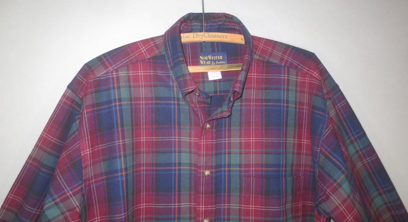 May include: A red, blue, and green plaid long-sleeve button-down shirt with the label "New Yorker Wear" on the collar.