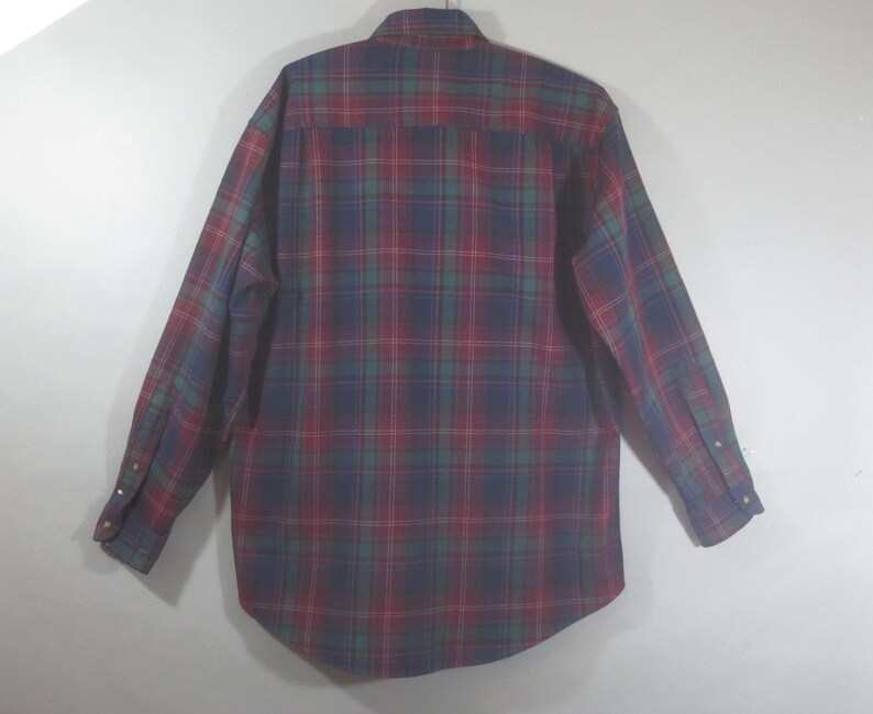 May include: A long-sleeved plaid shirt with a red, green, and blue plaid pattern. The shirt has a button-down collar and button cuffs.
