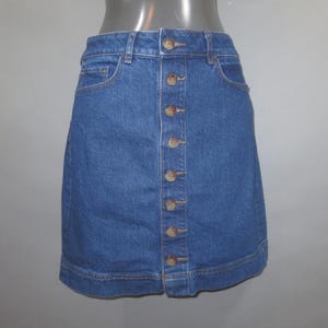 May include: A blue denim skirt with a button front closure. The skirt has a straight silhouette and a slightly flared hem.