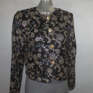 May include: A black blazer with a floral pattern and gold buttons. The fabric is covered in sequins and beads.