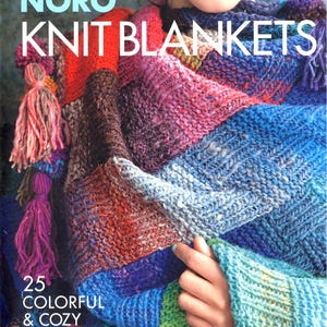 Puede incluir: Portada de libro con una colorida manta de punto. El texto dice "Timeless Noro Knit Blankets" y "25 Colorful & Cozy Throws". La manta es un mosaico de azules, rojos, morados y verdes, con borlas.