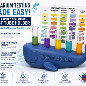 May include: A blue 3D printed whale-shaped test tube holder with the text INSERT LAB NAME, holding five glass test tubes filled with coloured liquids, positioned in front of a Freshwater Master Test Kit colour chart with pH, ammonia, nitrite, and nitrate levels.