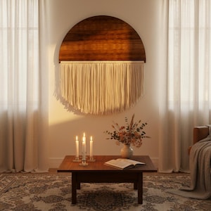 May include: A wooden wall hanging with a half-circle design, featuring a dark brown wood top and cream-colored fringe. The room includes a wooden coffee table, candles, a vase of flowers, and a patterned rug, creating a cozy atmosphere.