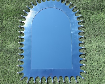 Espejo mexicano de hojalata hecho a mano, con forma arqueada y detalles de púas para decoración de pared.