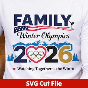 Könnte beinhalten: Weißes Langarmshirt mit einem Grafikdesign für die Olympischen Winterspiele 2026. Das Design enthält das Wort "FAMILY", die amerikanische Flagge und die Worte "Winter Olympics". Die Zahl "2026" ist in Blau und Gold gehalten, mit den olympischen Ringen in einem Herzen.