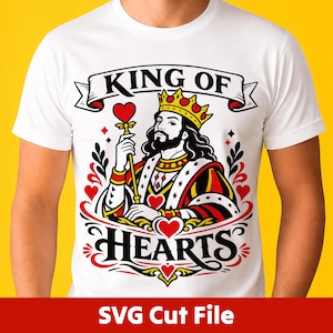 May include: A white t-shirt featuring a graphic illustration of a king wearing a crown and holding a heart-topped scepter. The design includes the text "KING OF HEARTS" in black lettering, surrounded by red heart motifs and decorative black flourishes.