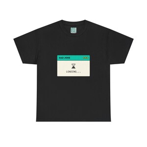 May include: Black t-shirt with a computer-style graphic that reads "DAD JOKE" at the top, and "LOADING..." below an hourglass icon. The shirt has a crew neck and short sleeves.