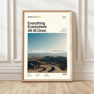 Puede incluir: Un póster enmarcado de la película "Everything Everywhere All At Once". El póster presenta el título en negrita, en texto negro, con una escena de paisaje desértico bajo un cielo azul. El póster incluye el texto "ha ha ha ha ha" y el año "/2022".