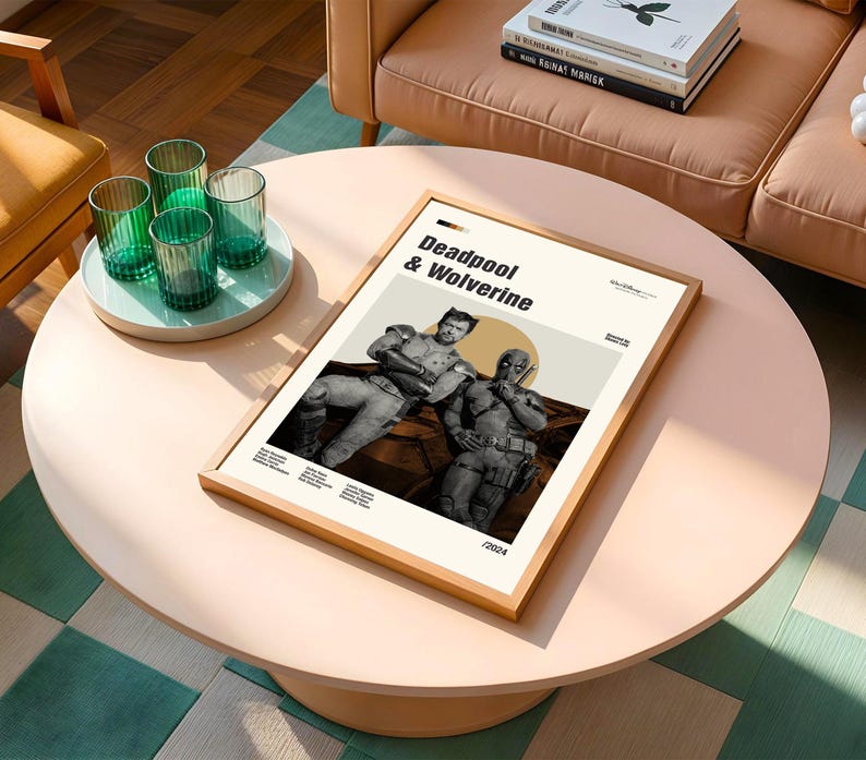 May include: A framed poster featuring Deadpool and Wolverine. The poster has a light beige background with the title "Deadpool & Wolverine" in bold black text. The image shows the two characters in a sepia tone. The frame is made of light wood.