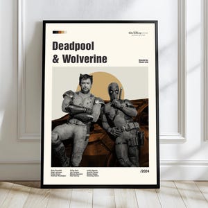May include: A framed poster featuring Deadpool and Wolverine. The poster has a beige background with the title "Deadpool & Wolverine" in bold black letters. The image shows the two characters in costume, with a sun-like shape behind them. The poster is framed in black.