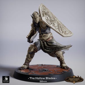 May include: A detailed figurine of a warrior in ornate armor, holding a shield and a blade. The figure is predominantly gray and beige, with intricate detailing on the armor and shield. The base is black with the text "- The Hollow Blades - 32mm".