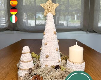 May include: A handmade Christmas centerpiece featuring a crocheted tree with a gold star topper, a smaller tree, and a candle. The arrangement is set on a wooden base with moss and pinecones. The text "pdf pattern and video" is visible.