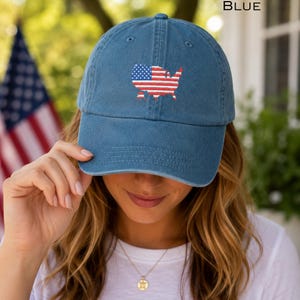 May include: Blue baseball cap with an embroidered American flag design. The cap features a curved brim and an adjustable strap. The word "BLUE" is printed on the top right corner of the image.
