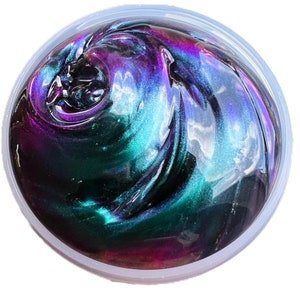 May include: A close-up of iridescent slime in a clear plastic container. The slime is a dark green color with hints of purple and blue.