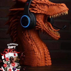 Può includere: Un supporto per cuffie a forma di testa di drago arancione, con cuffie nere con luce blu. Il drago ha denti affilati e una superficie strutturata. È visibile anche una confezione regalo con la scritta "SURPRISE GIFT".