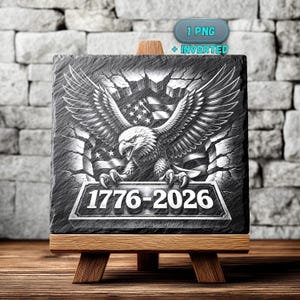 May include: A black and white slate coaster featuring a detailed illustration of an American bald eagle with outstretched wings, the American flag, and the years 1776-2026. The coaster is displayed on a small wooden easel.