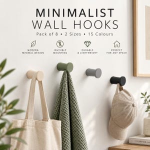 May include: A set of cylindrical wall hooks in beige, sage green, grey, and black. The text reads MINIMALIST WALL HOOKS, Pack of 8, 2 Sizes, 15 Colours, MODERN MINIMAL DESIGN, INVISIBLE MOUNTING, DURABLE & LIGHTWEIGHT, and PERFECT FOR ANY SPACE.