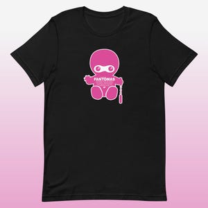 Może przedstawiać: Czarny t-shirt z różową postacią z kreskówki ninja i napisem "FANTOMAS SUSPENDED ANIMATION". Ninja ma maskę i trzyma łańcuch z różowym przedmiotem. Koszulka jest wykonana z miękkiego materiału.