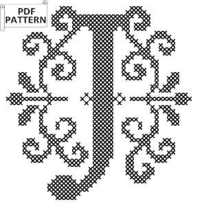 May include: Black and white cross stitch pattern of a stylized letter 'J' with ornate floral details.
