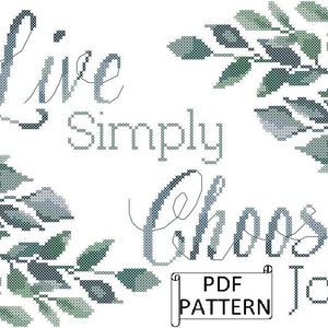 May include: Cross stitch pattern featuring the text "Live Simply Choose Joy" with a leafy border. The pattern is available as a PDF download.