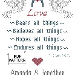 May include: A cross-stitch design on white fabric. The word "Love" is stitched in red, with a heart above it. The text includes "Bears all things," "Believes all things," "Hopes all things," and "Endures all things." The names "Amanda & Jonathan" and the date "08.23.14" are also stitched.