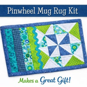 May include: A rectangular pinwheel mug rug kit with a blue border. The center features a pinwheel design in blue, white, and green. The text "Pinwheel Mug Rug Kit" and "Makes a Great Gift!" are displayed.