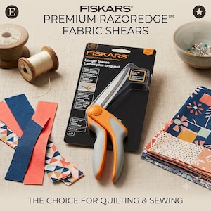 May include: Fiskars Premium RazorEdge fabric shears in black and orange packaging. The shears feature long metal blades and ergonomic orange and gray handles. The packaging includes the text Fiskars Premium RazorEdge Fabric Shears.