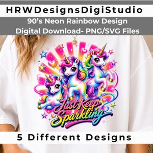 May include: A white t-shirt featuring a graphic of three colorful unicorns with rainbow manes and gold horns, surrounded by neon stars and hearts. The text reads Just Keep Sparkling in a stylized blue and pink font with a bright sunburst background.