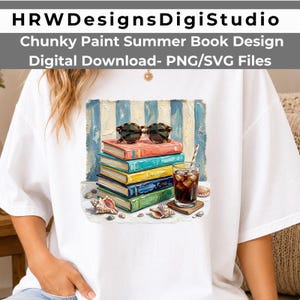 May include: A white t-shirt featuring a graphic print of a stack of colorful books topped with tortoiseshell sunglasses, next to a glass of iced coffee with a straw and seashells, against a blue and white striped background with text above.