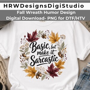Può includere: Una t-shirt bianca a maniche corte con una grafica circolare a ghirlanda autunnale composta da ghiande marroni e foglie d'acero colorate nei toni del rosso, arancione e giallo. Il testo centrale recita Basic, but make it Sarcastic in nero.