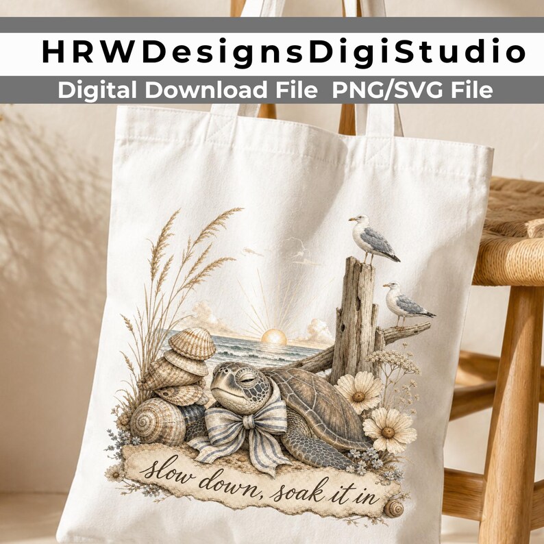 May include: A white canvas tote bag featuring a printed illustration of a sea turtle wearing a striped bow, resting on a beach with seashells, tall grass, two seagulls perched on driftwood, and a sunset, with the text "slow down, soak it in".
