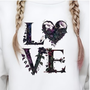 K&ouml;nnte beinhalten: Ein wei&szlig;es Sweatshirt mit dem Wort LOVE in gro&szlig;en Gro&szlig;buchstaben. Die Buchstaben sind mit dunkelvioletten und gr&uuml;nen botanischen Illustrationen verziert, darunter Ranken, Bl&auml;tter und Beeren. Der Buchstabe O ist durch ein Herz ersetzt.
