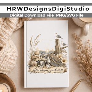 May include: A white notebook featuring a printed illustration of a sea turtle wearing a bow, stacked seashells, tall beach grass, two seagulls perched on a wooden post, and a sunset over the ocean with the text "slow down, soak it in".