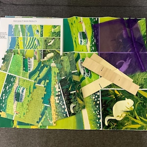 Pu&ograve; includere: Un puzzle da 500 pezzi parzialmente assemblato con una scena di paesaggio verde e bianco. I pezzi del puzzle sono sparsi su una base stampata colorata, con un sacchetto viola e supporti in legno. La scatola recita "HIGH QUALITY WOOD PRODUCTS".