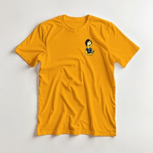 Op de afbeelding: Mosterdgeel t-shirt met een cartoon illustratie van een man met een snor en de tekst "Escobar". De afbeelding is in zwart, blauw en geel. Het shirt is gemaakt van een zacht materiaal.