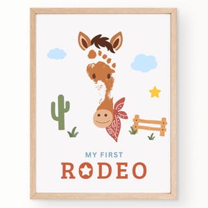 May include: A framed wall art print featuring a brown horse illustration created from a footprint. The horse wears a red patterned bandana. The design includes a green cactus, a wooden fence, blue clouds, a yellow star, and the text MY FIRST RODEO.