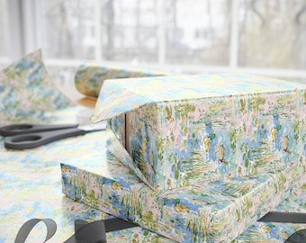 May include: Wrapping paper featuring a repeating pattern of mallard ducks swimming in a pond with green reeds and lily pads on a light pink background. The paper is used to wrap rectangular boxes, with black ribbon and scissors nearby.
