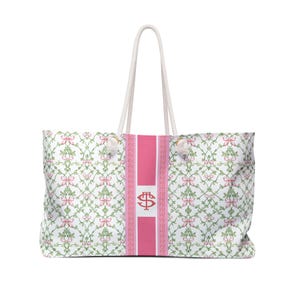 May include: Large white tote bag with a pink vertical stripe and a floral pattern of pink bows and green vines. The bag has white rope handles and a pink center stripe with a logo.