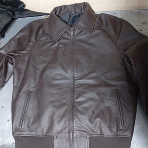 Puede incluir: Chaqueta de cuero marr&oacute;n con cremallera, cuello y dos bolsillos delanteros. La chaqueta tiene dobladillo y pu&ntilde;os acanalados. El cuero tiene un aspecto texturizado. La chaqueta es de estilo cl&aacute;sico.
