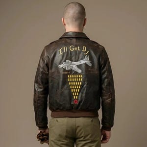 以下が含まれることがあります： 背面に「I'll Get By」という黄色の文字、銀色の飛行機のイラスト、黄色の爆弾アイコンの三角形の編隊、そして小さな赤い円形のエンブレムが描かれた、ダークブラウンのレザー製ボンバージャケット。