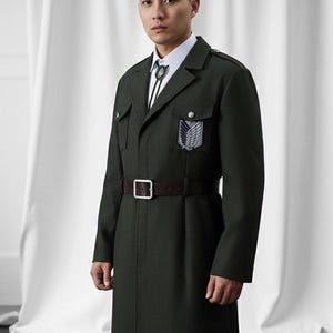 以下が含まれることがあります： 茶色のベルトと白いシャツが付いた濃い緑色のコート。コートには翼のあるエンブレムのパッチが付いています。コートはクラシックなデザインで、体に合ったフィット感です。コートは重い素材で作られています。